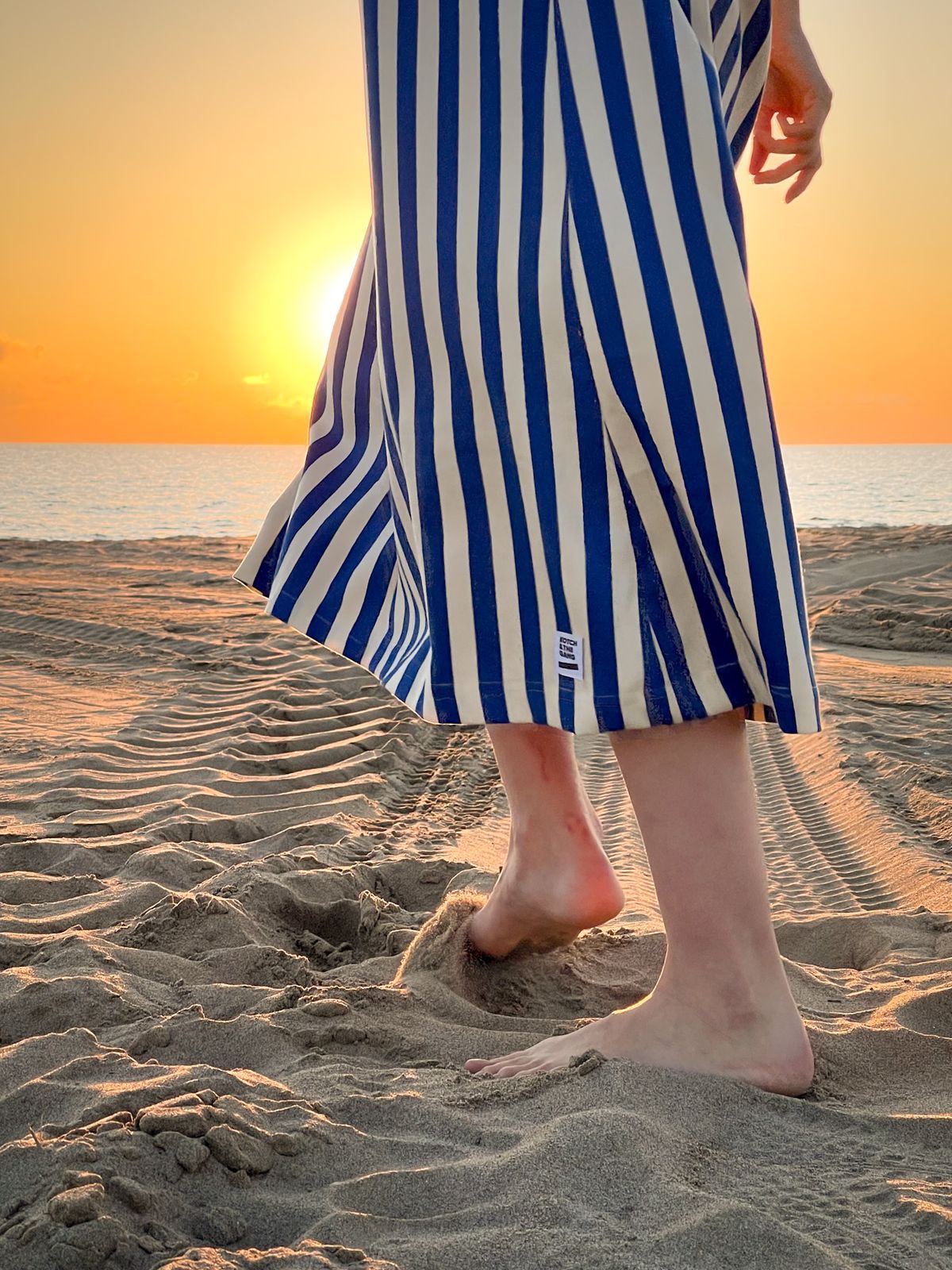 Robe rayée bleu et blanc au coucher du soleil sur la plage