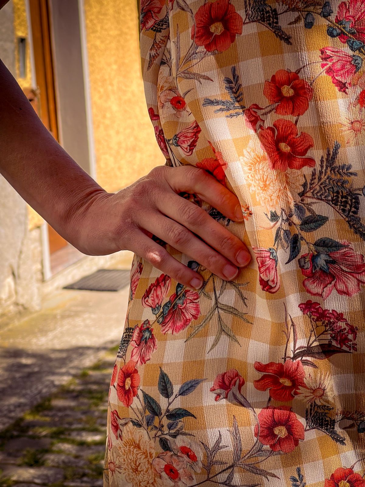 Détail d’une robe fleurie, main sur la hanche
