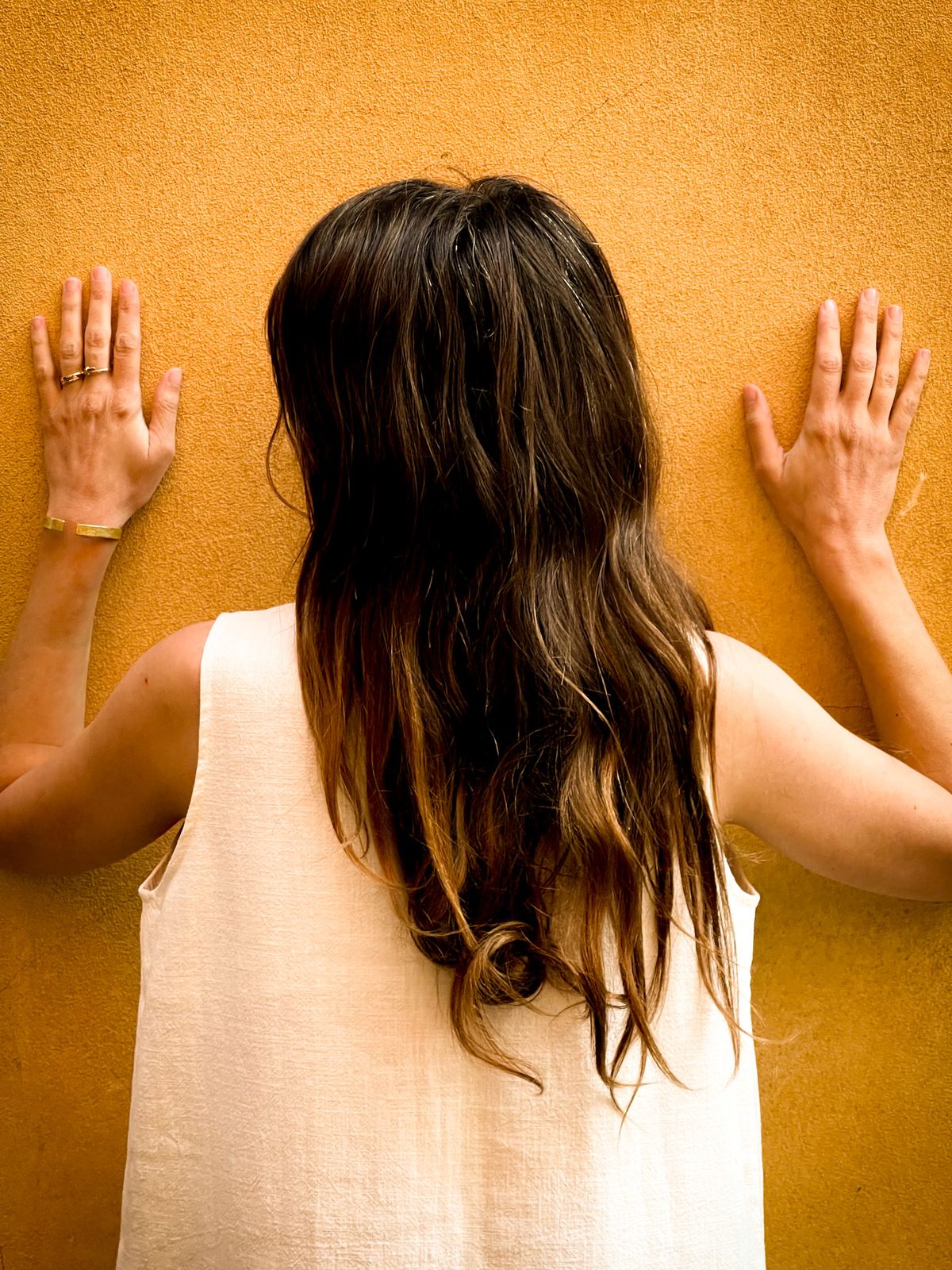 De dos, mains contre un mur ocre