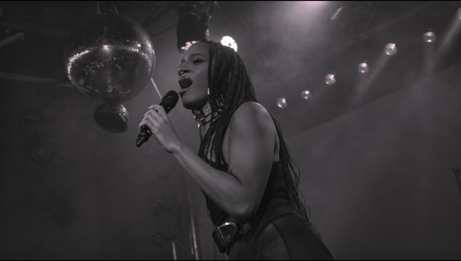 Chanteuse au micro sous les projecteurs, noir et blanc