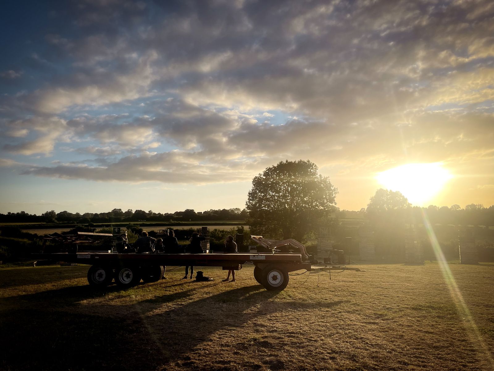 Soleil couchant sur un champ et une remorque agricole