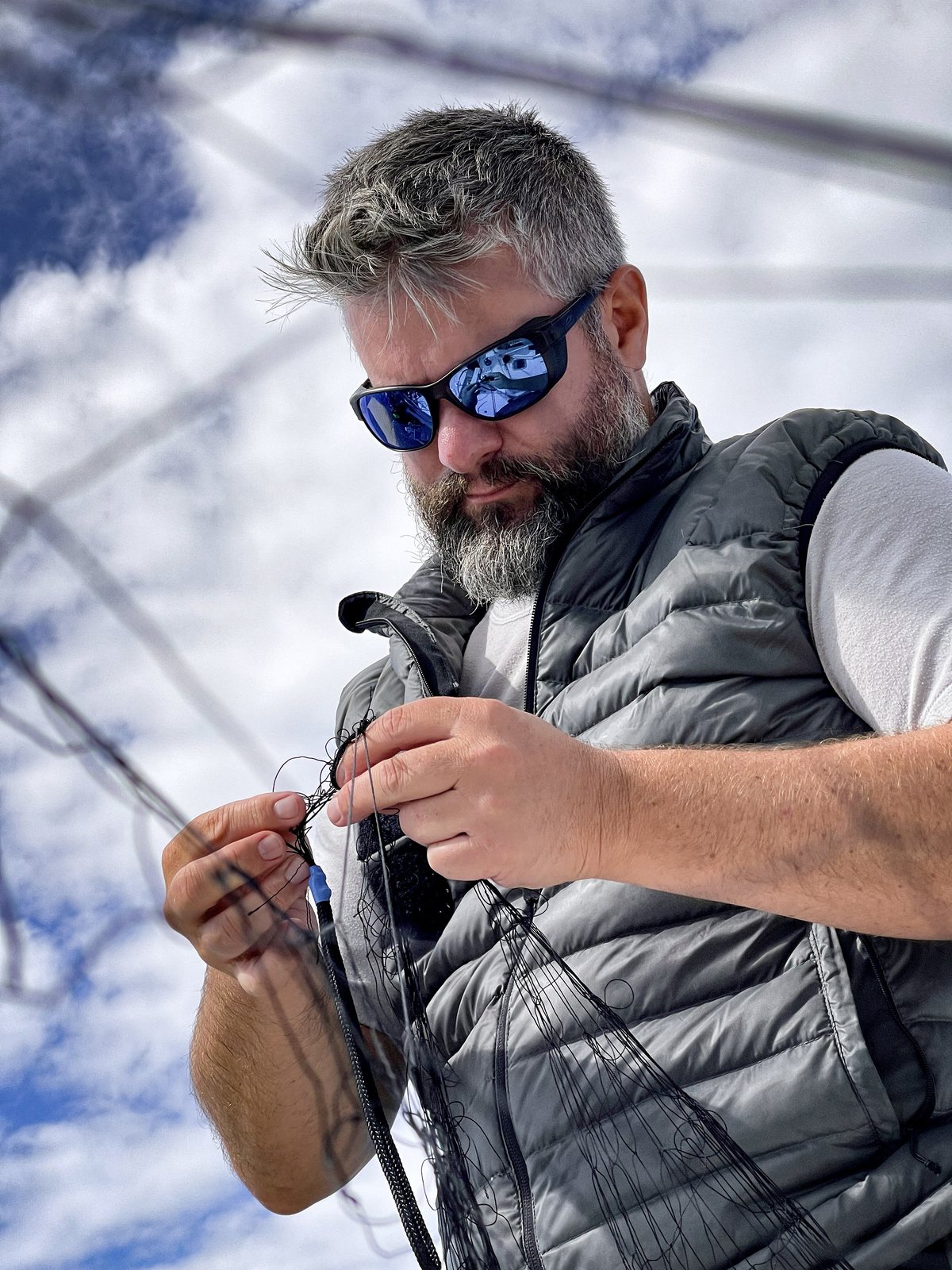 Navigateur aux lunettes de soleil nouant un cordage à bord