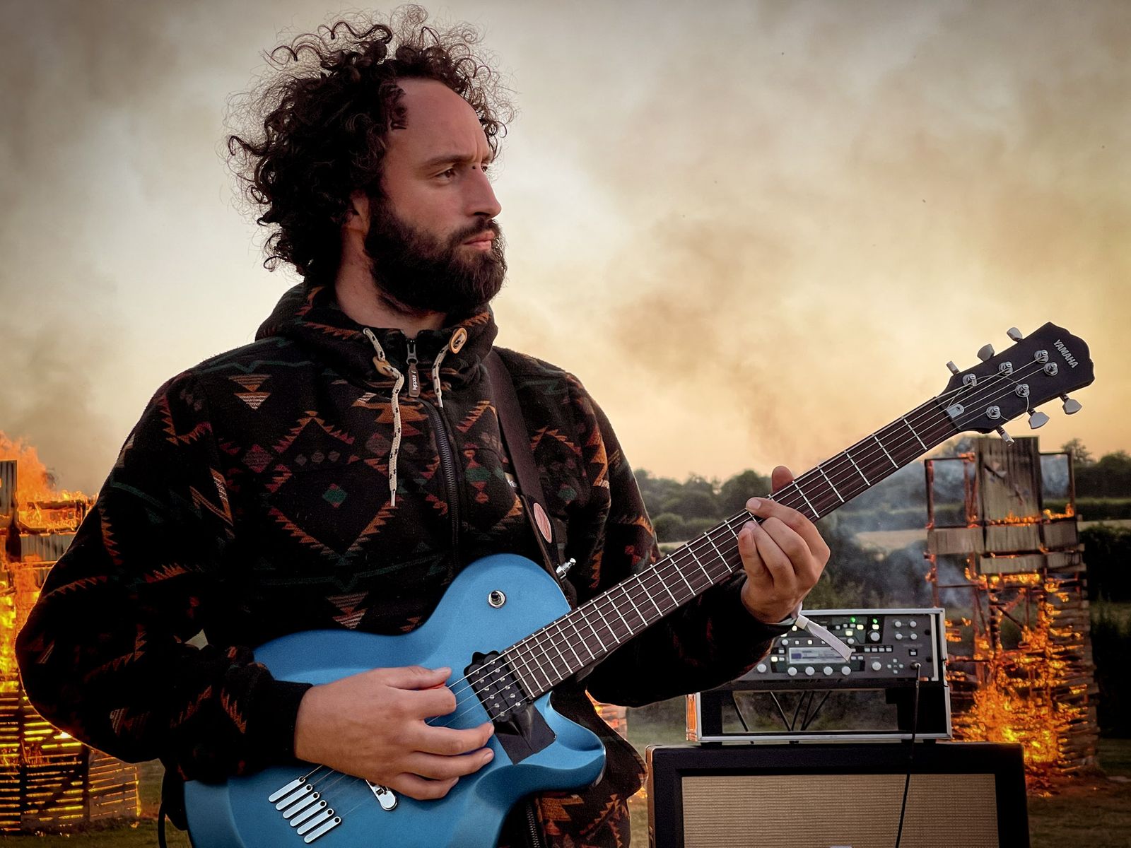 Guitariste devant un brasier au coucher du soleil