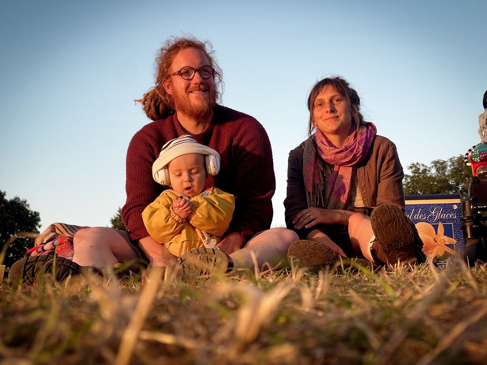 Famille assise dans l’herbe au soleil couchant