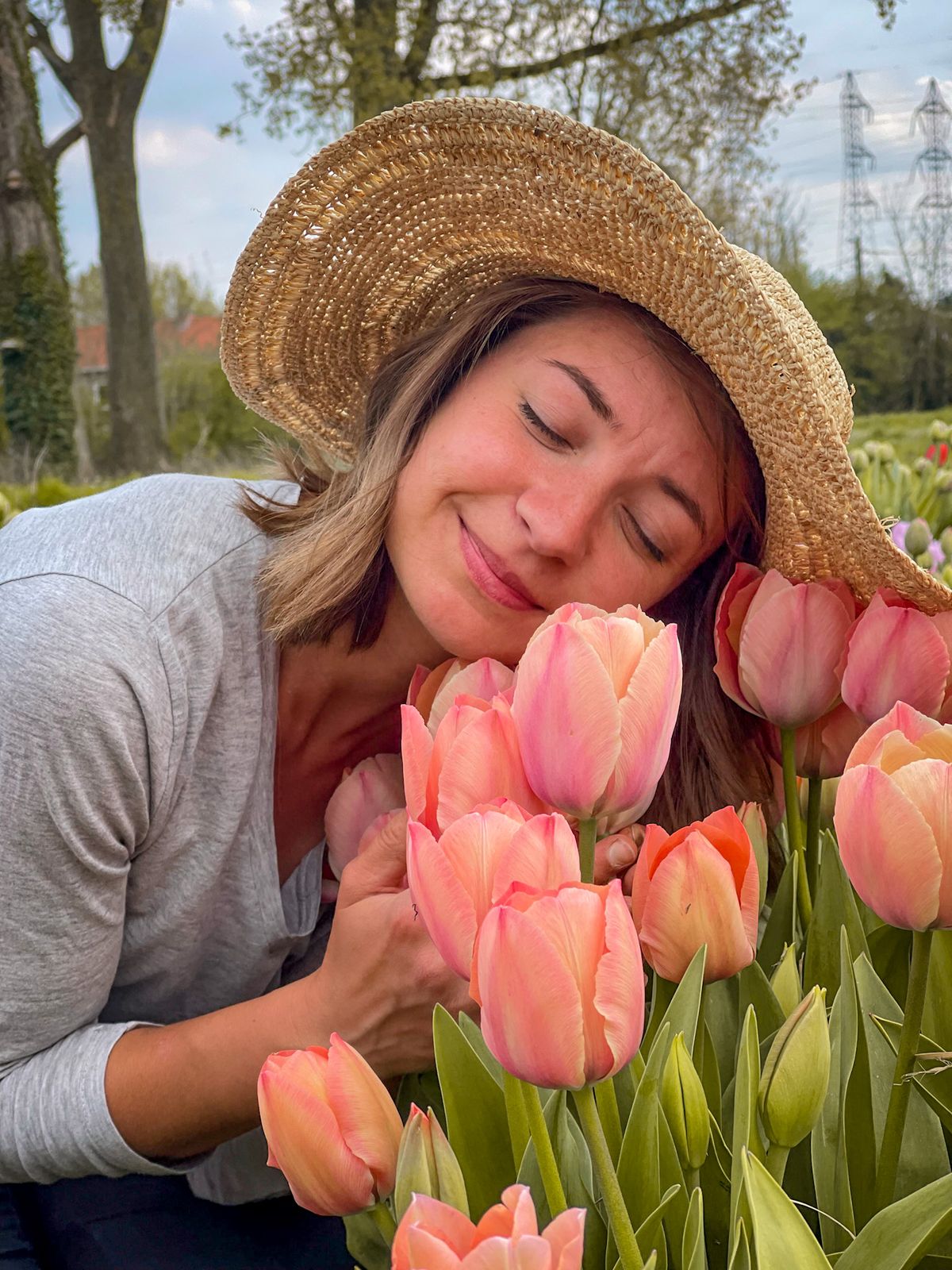 Productrice de fleurs au chapeau de paille, joue contre les tulipes